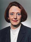 Woman with red hair poses in a white shirt and a blazer.