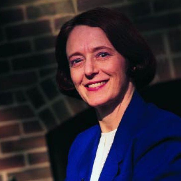 Portrait of professor Olivia Mitchell wearing a blue formal jacket and a white shirt underneath.