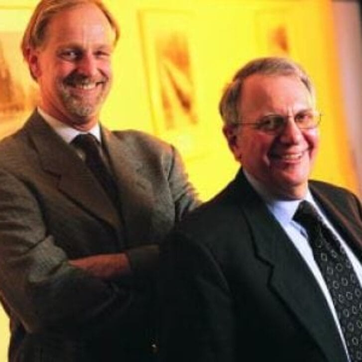 Two men in business suits pose together for a photo.