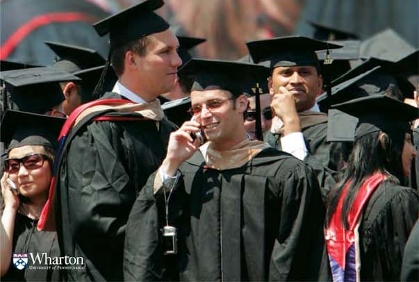 Wharton students gathered at graduation with a few talking on the phone.