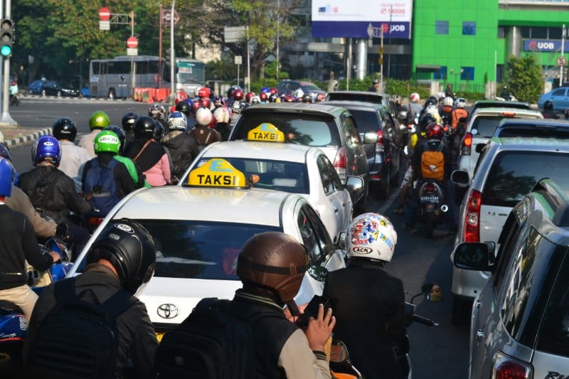 Traffic congestion in Jakarta. Motorcycle riders multitasking while waiting.