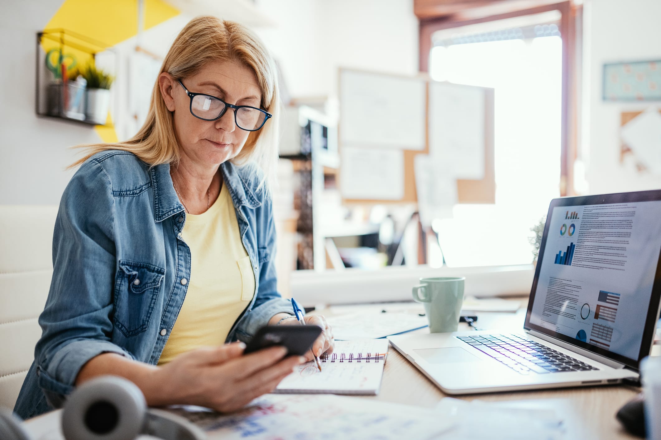 Woman using phone and laptop to work