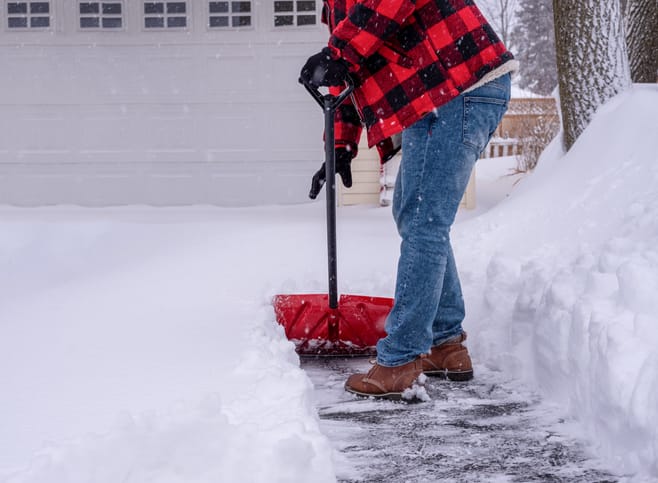A man shoveling the driveway after a heavy snowfall.
