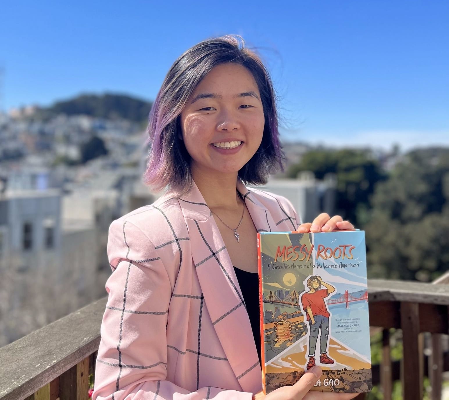 Laura Gao, author of the graphic Messy Roots, posing with the book.