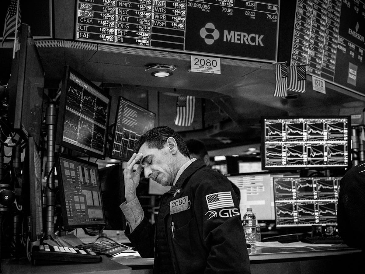 A stock-market trader rubbing his forehead in frustration.