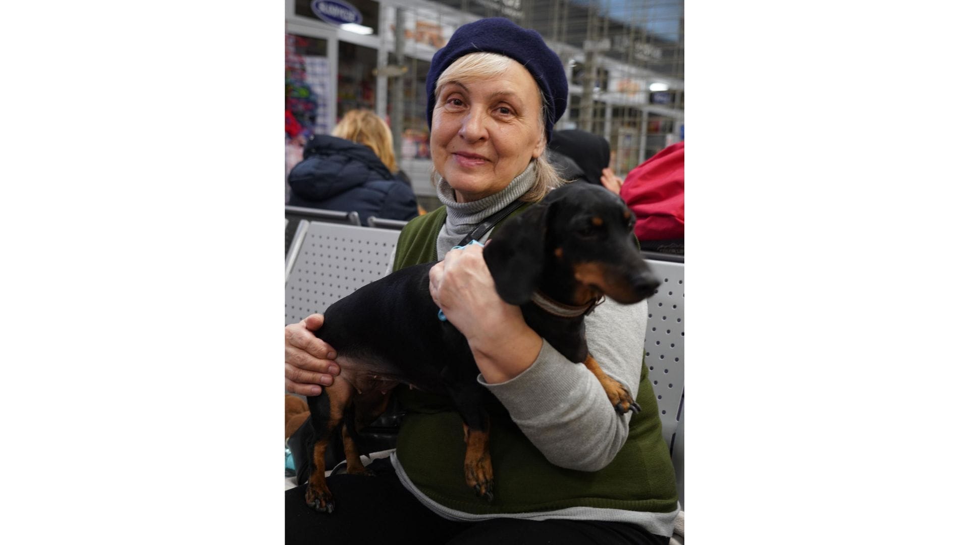 A woman holding a dog in a bus station in Poland.