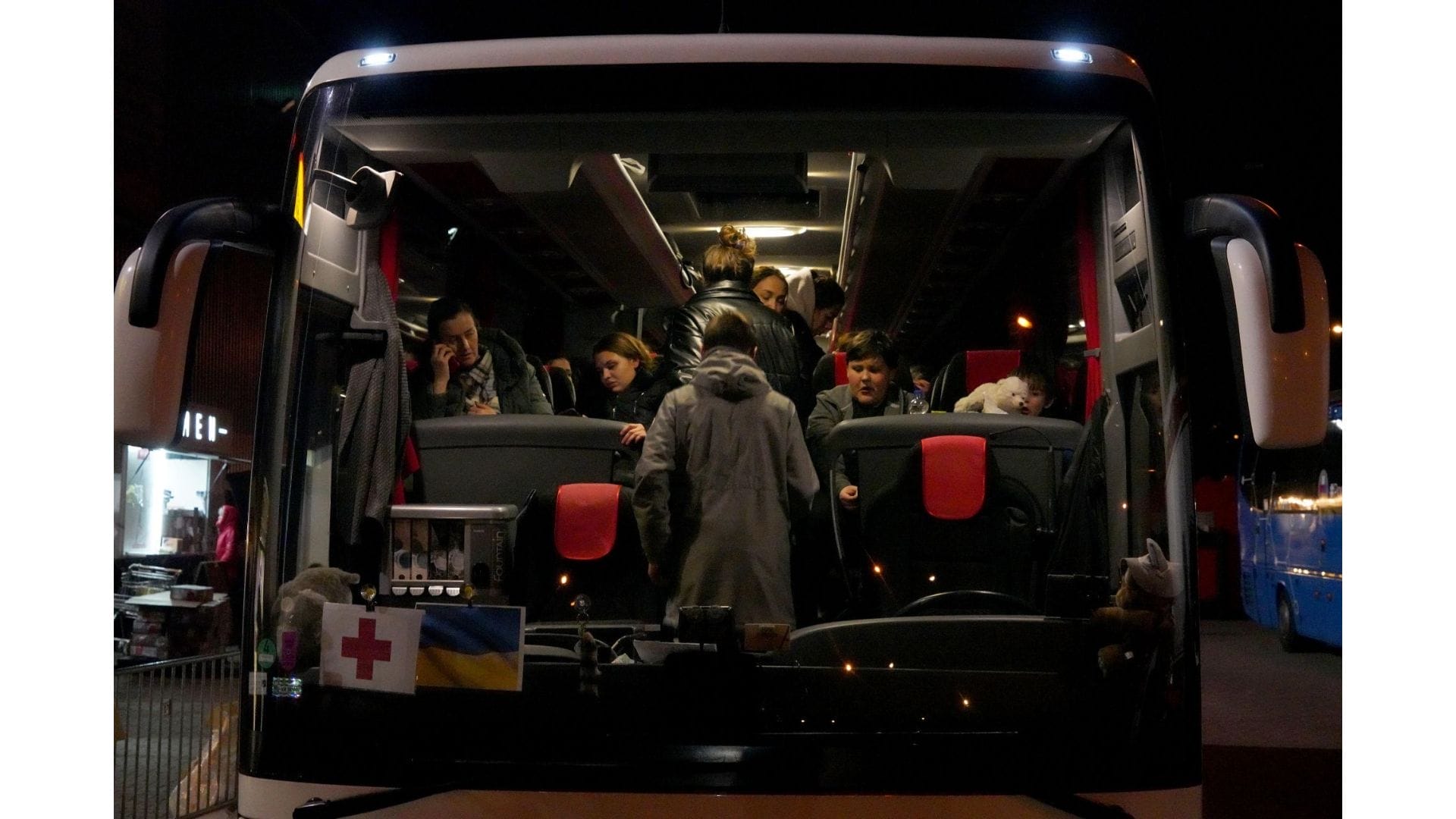 Ukrainian refugees on a bus as seen through a bus window.