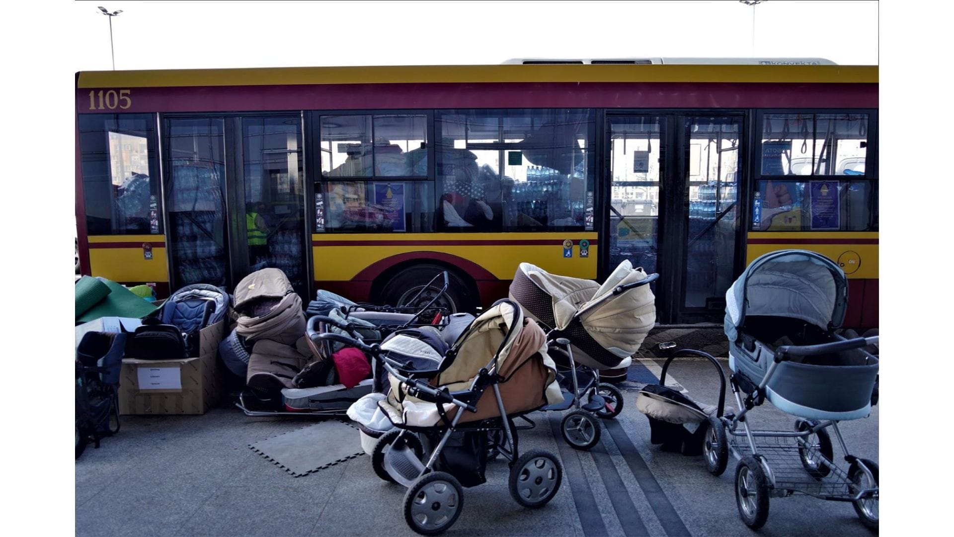 Several strollers beside a bus.