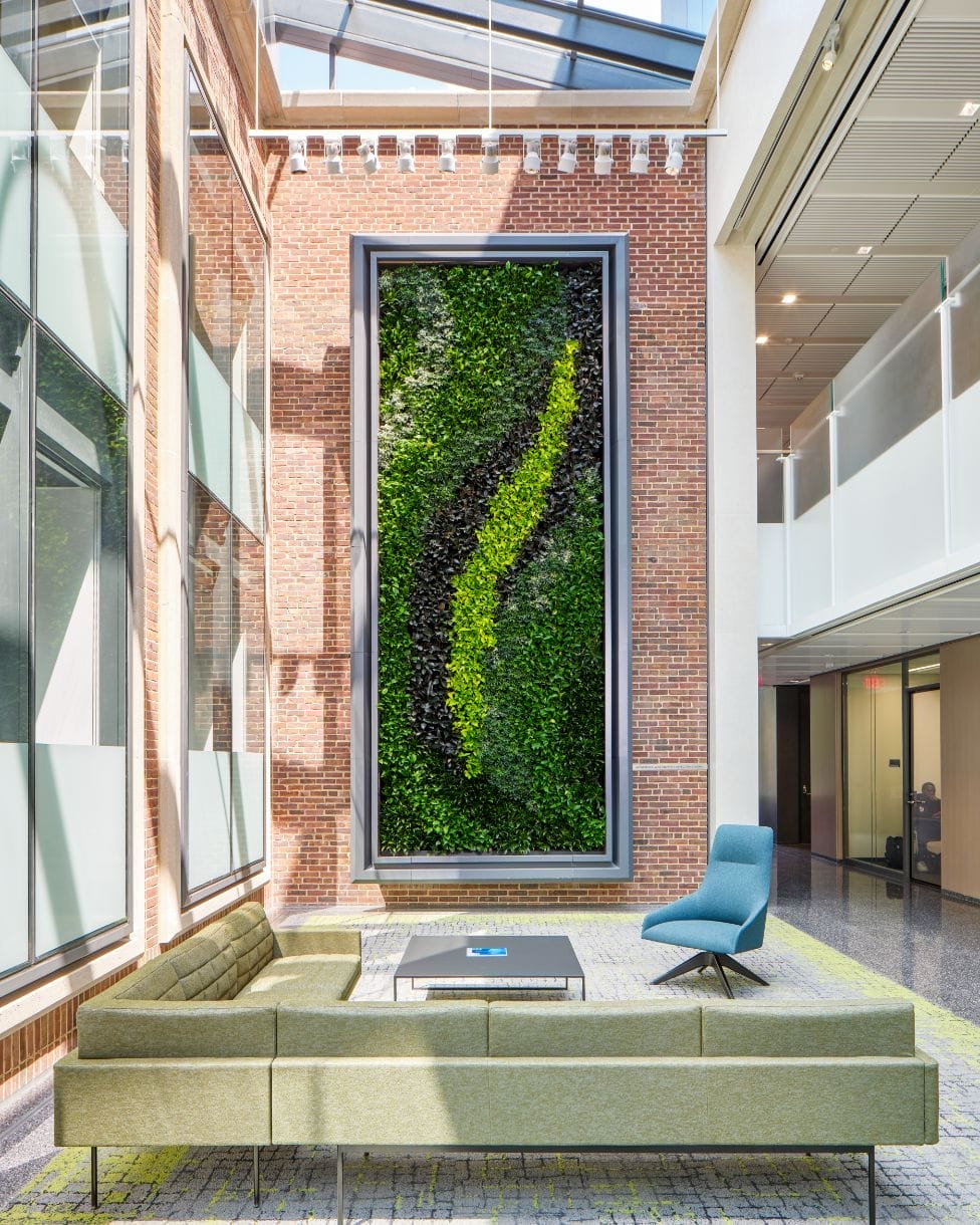 Red brick living wall with framed vines in a lounge decorated with modern furniture.