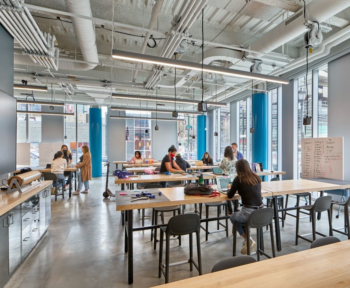 Picture of students seated at long wooden tables in the Fabrication Studio in Tangen Hall.