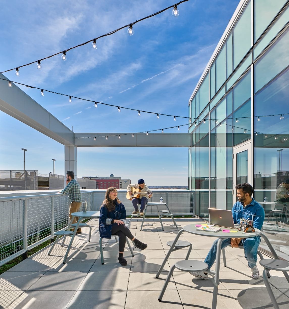 Students taking in outside views, playing a guitar, working on a laptop, and more on Tangen Hall's rooftop terrace.