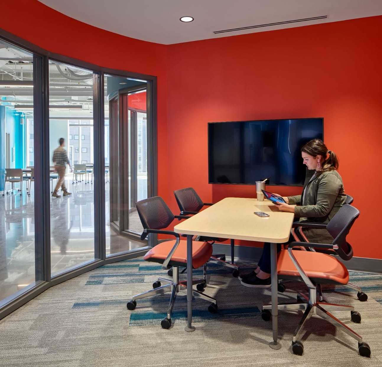A woman working in a workspace equipped with a table, chairs, and a television in Tangen Hall.