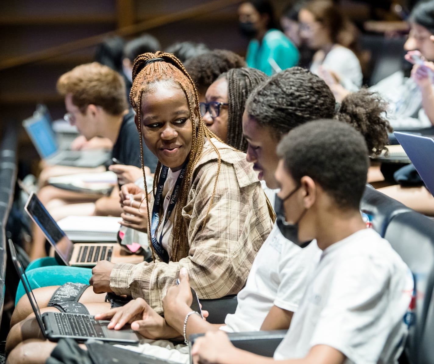Students in a lecture hall seated with laptops.
