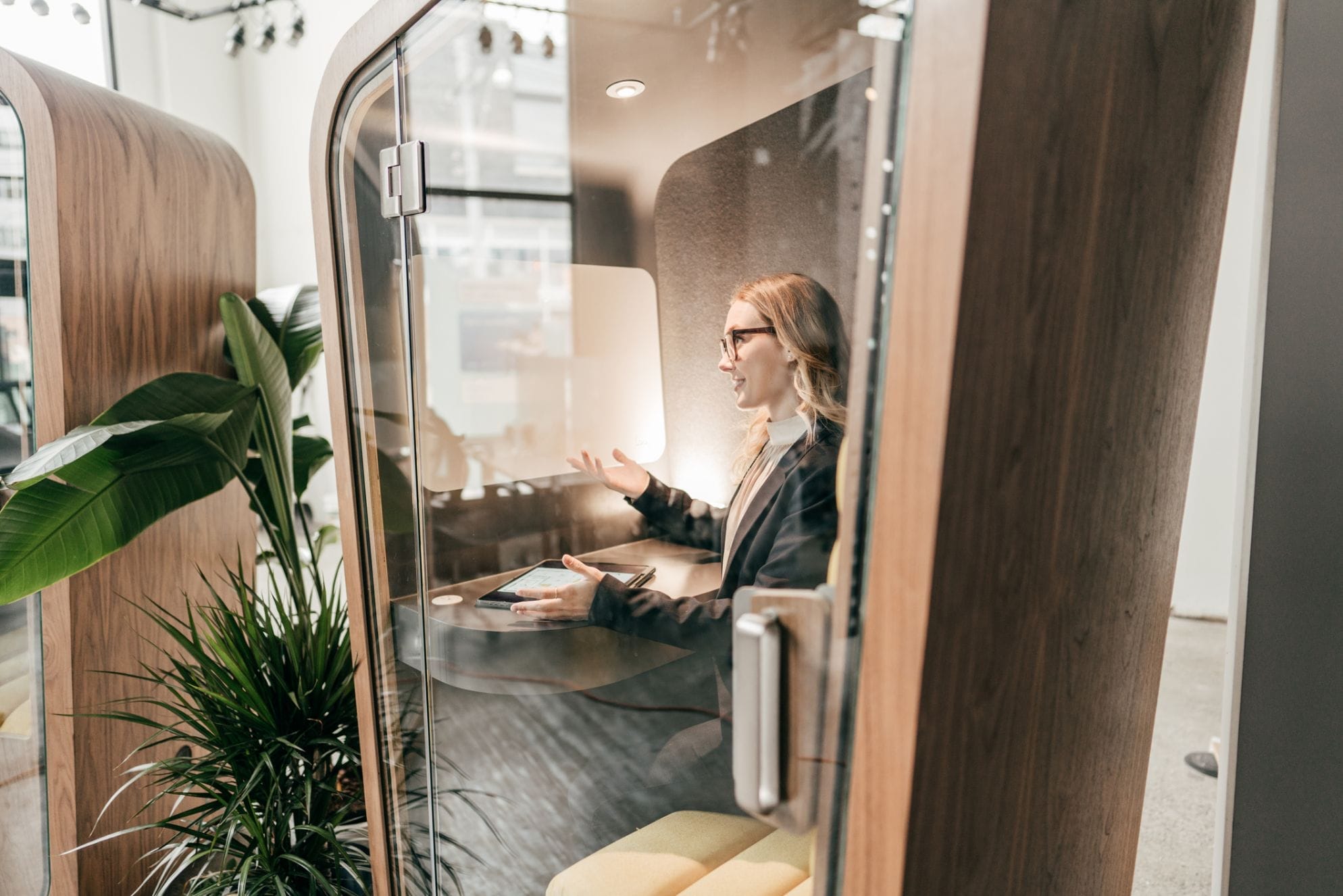 A woman speaking in an enclosed office pod.