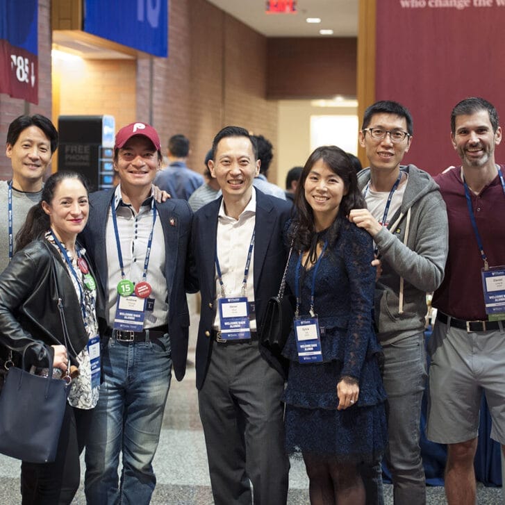 Nine attendees at Wharton Reunion Reimagined pose for a photo together in Huntsman Hall.