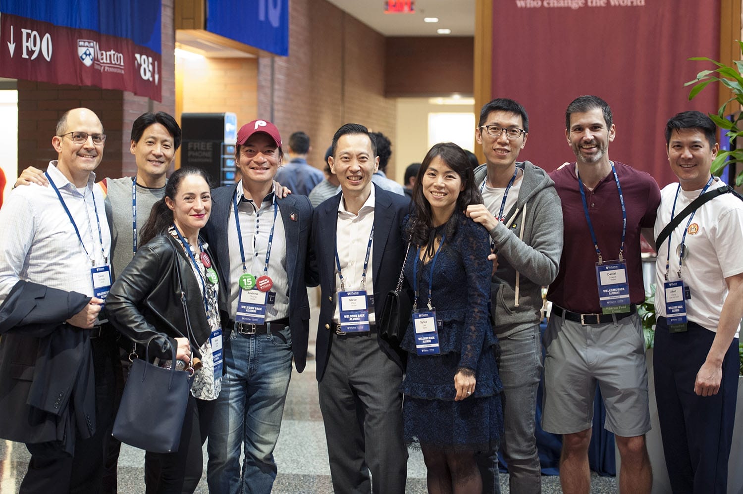 Nine attendees at Wharton Reunion Reimagined pose for a photo together in Huntsman Hall.