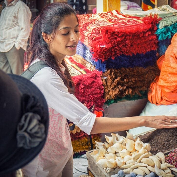 Photo of alumna Arva Ahmed standing before spices in a market.