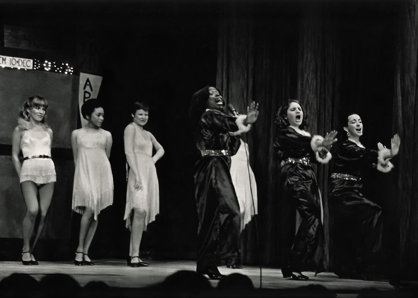 Six female performers sing on stage for a past Follies performance.