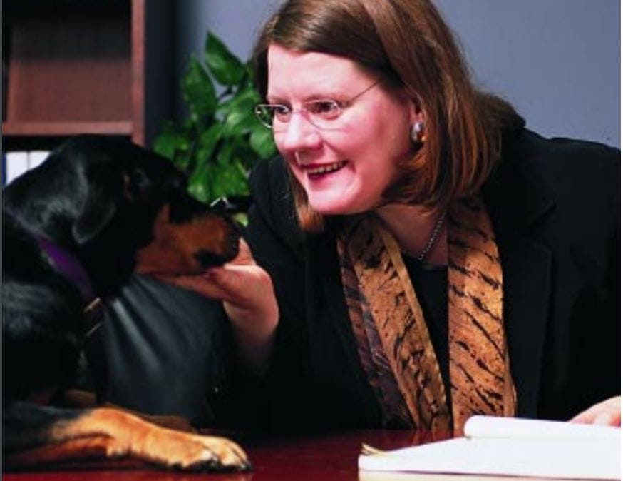 Alumna Angelique Irvin sitting at a desk with a dog