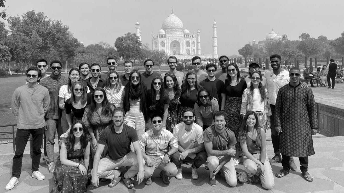 A group of students pose together for a photo in front of the Taj Mahal.
