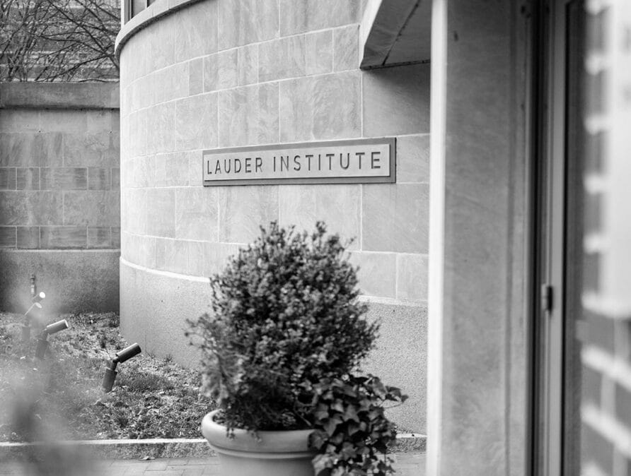 A brick wall with a plaque with the words "Lauder Institute" on it.