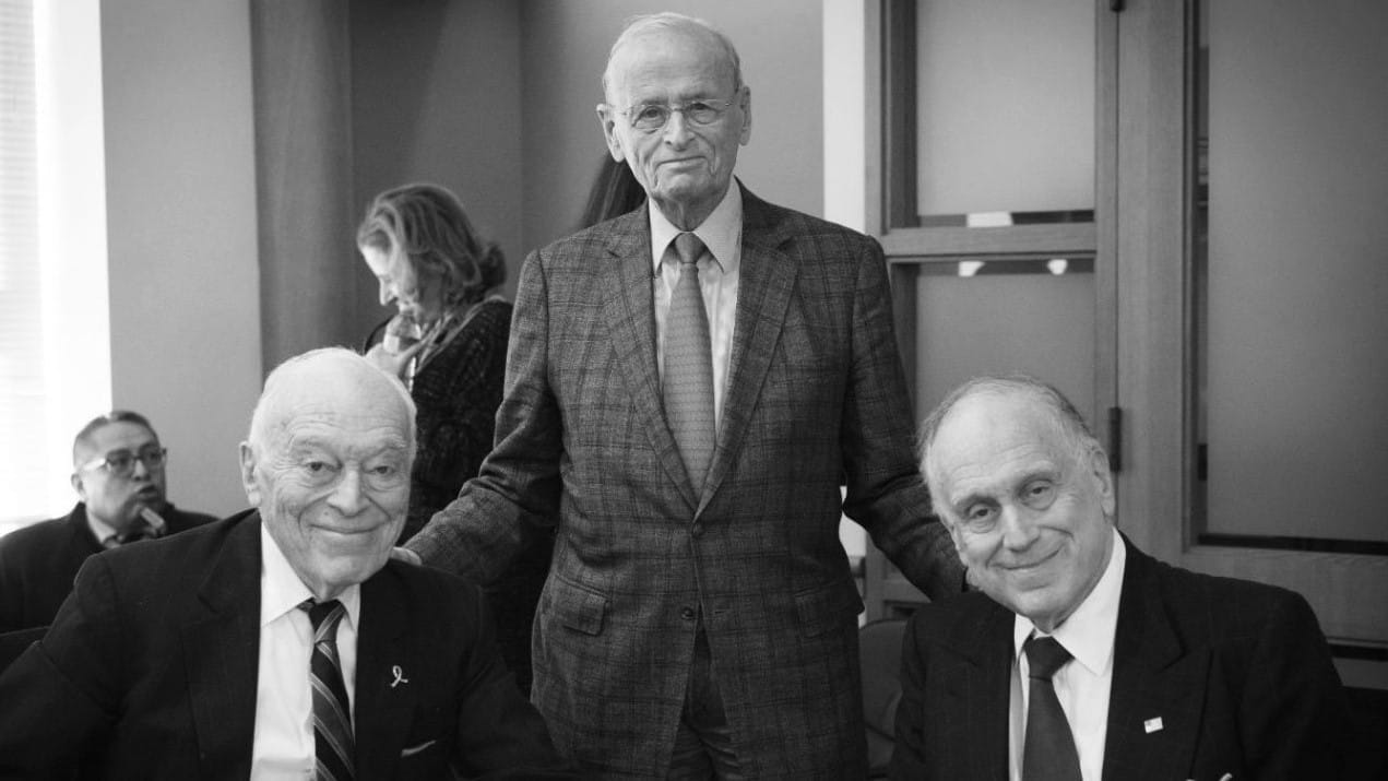 Three men in suits and ties pose for a portrait together.