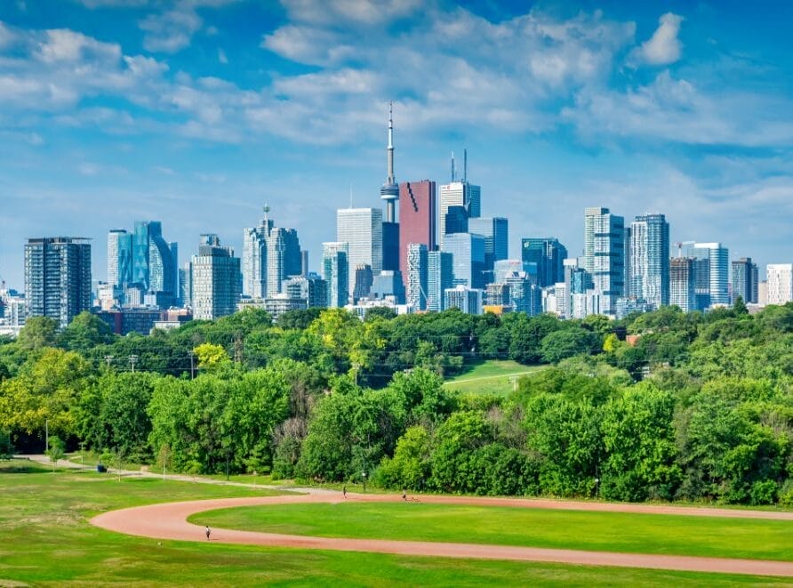 Cityscape of Toronto, with people walking in a park in the foreground.
