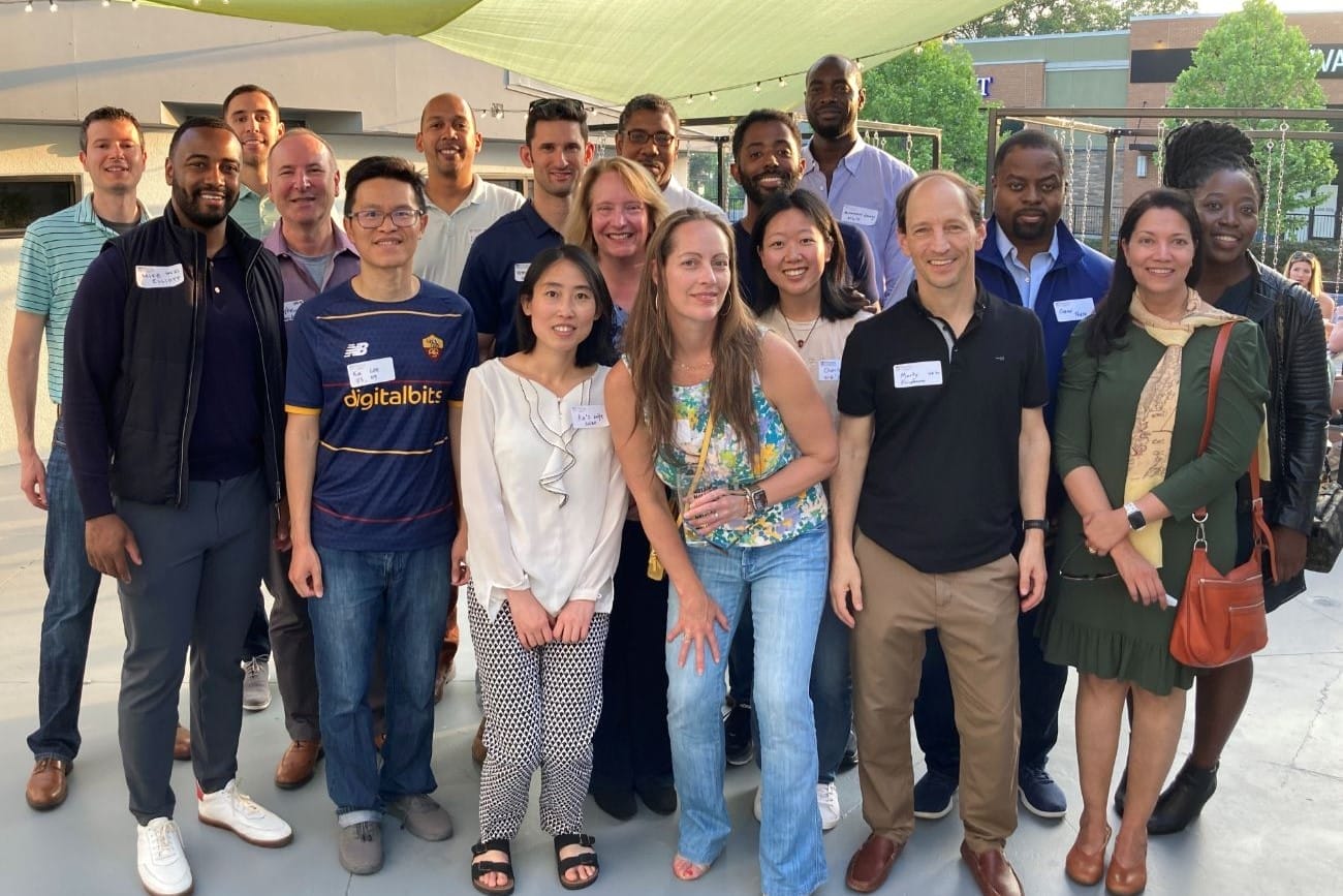 Eighteen people at an outdoor happy hour pose together.