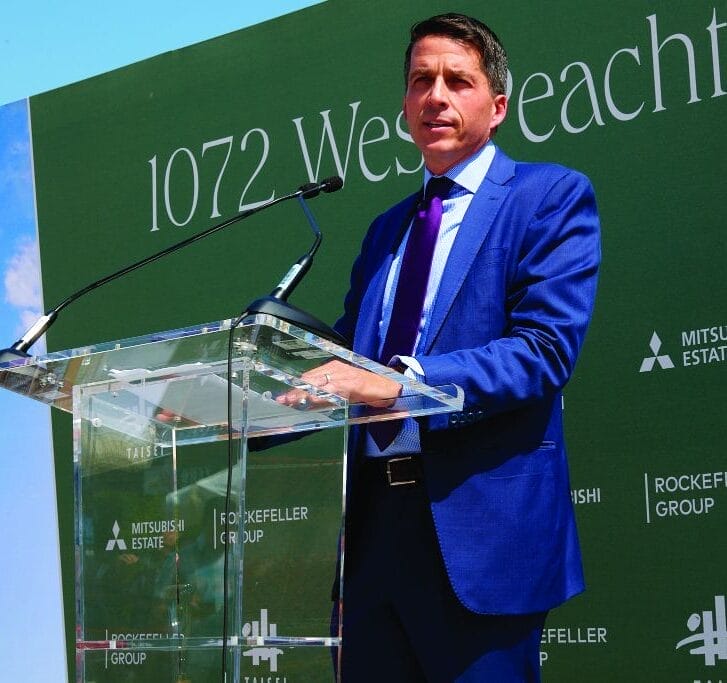 Dan Moore speaking at a podium during a building's groundbreaking