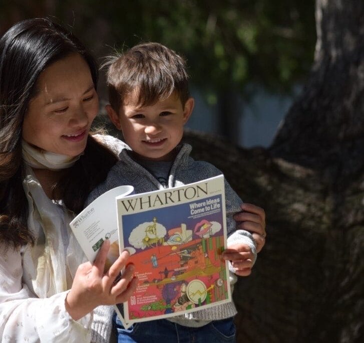 Mom and toddler-aged son reading Wharton Magazine