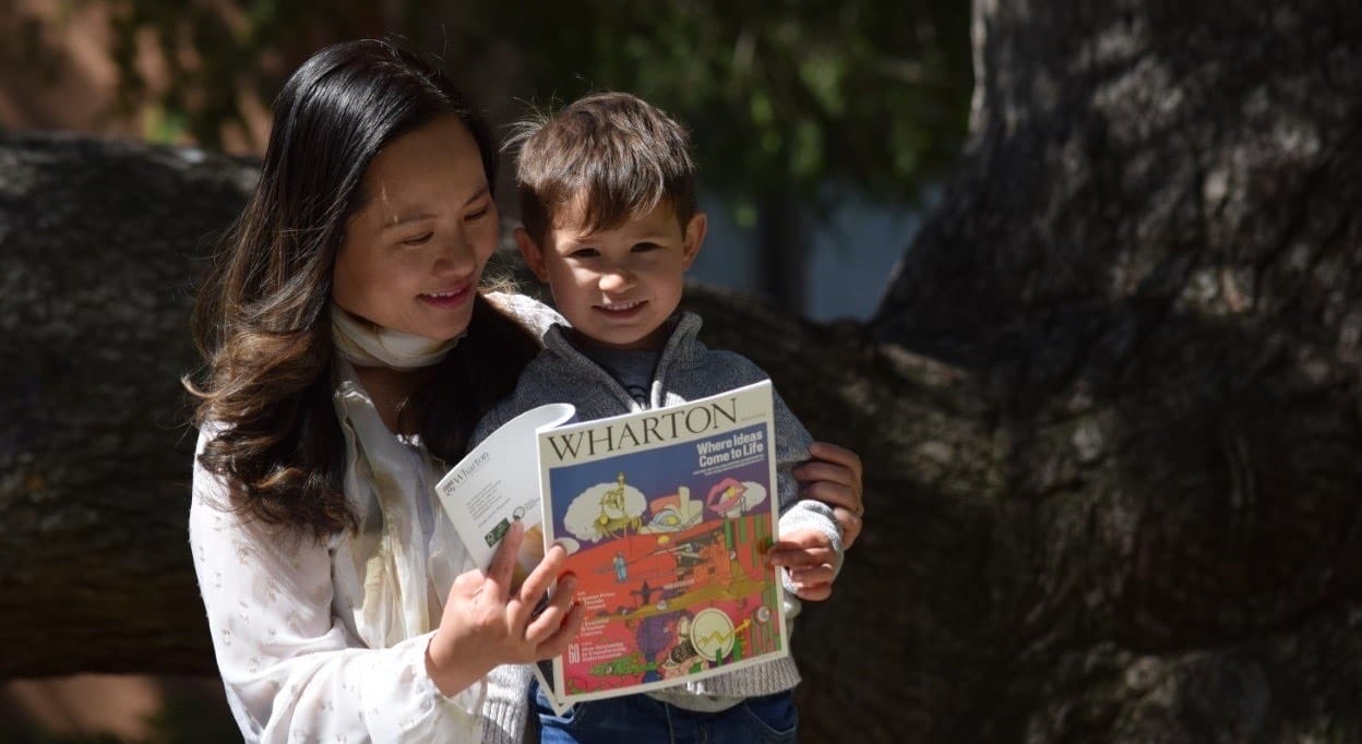 Mom and toddler-aged son reading Wharton Magazine