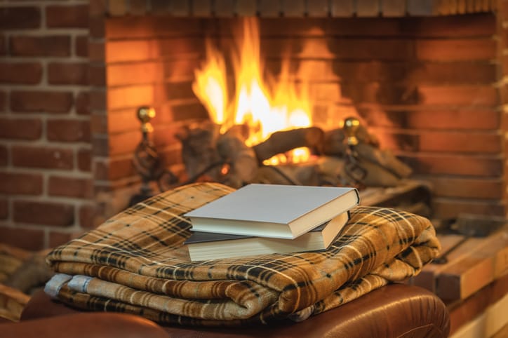 Stack of books in front of a fireplace.