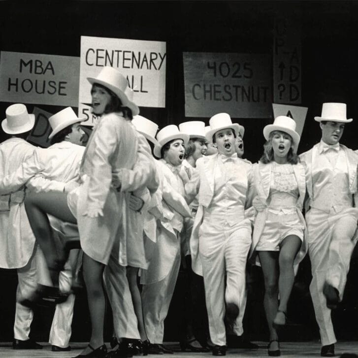 Follies performers dressed in white suit, skirts, and hats.