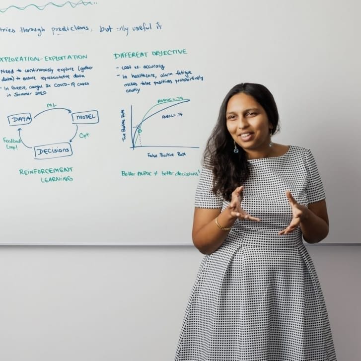 Professor Hamsa Bastani teaches at a whiteboard with key concepts written on it.