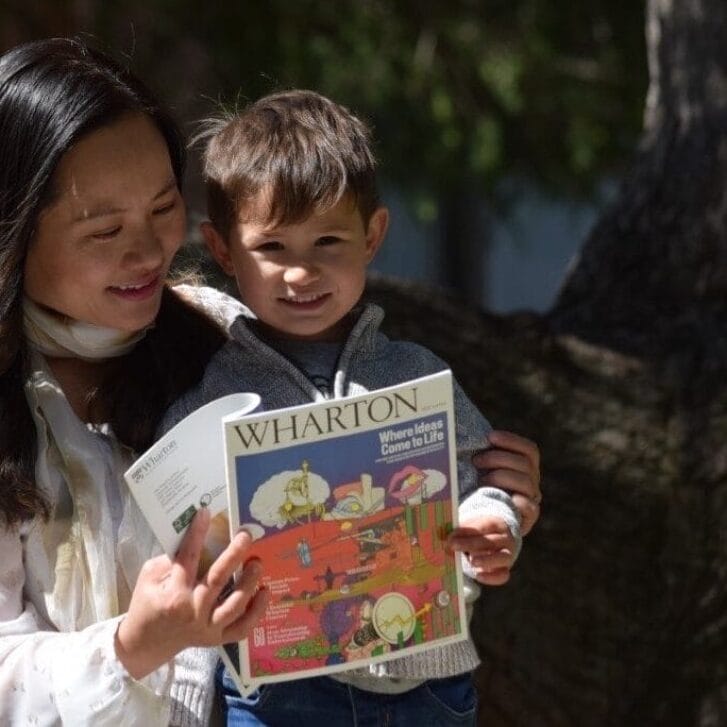 Mom and toddler-aged son reading Wharton Magazine