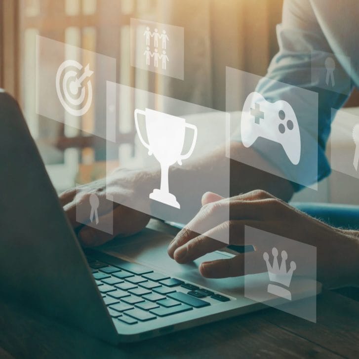 Conceptual image of a person playing educational games on a laptop and earning trophies, rewards, and more.