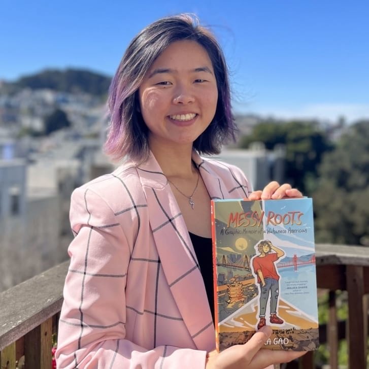 Laura Gao, author of the graphic Messy Roots, posing with the book.