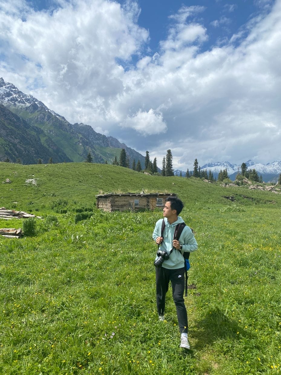 Self-portrait of author Jesse Zhang in a green field.