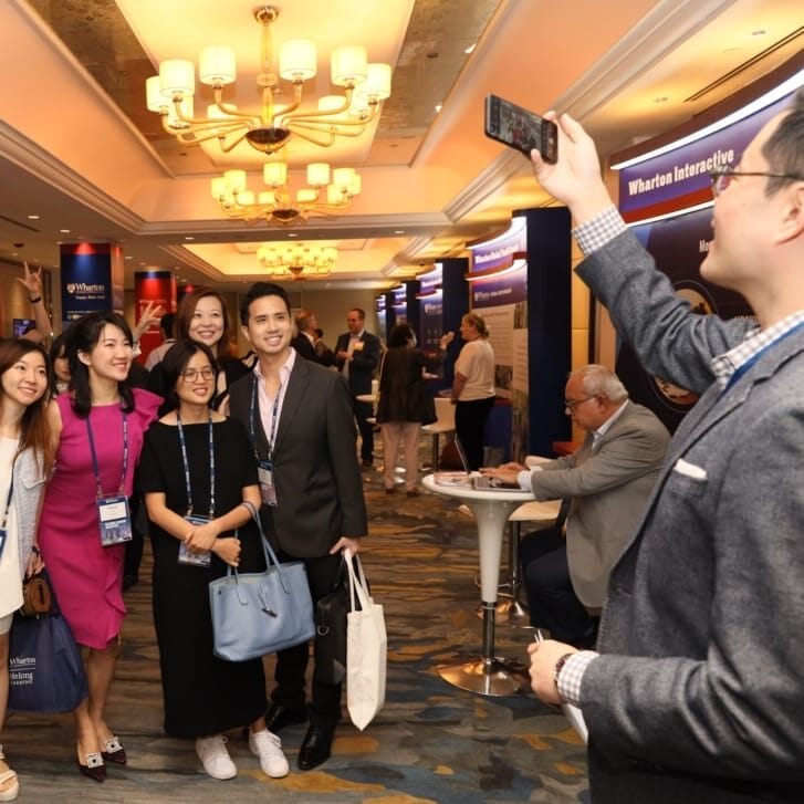 Attendees at the Wharton Global Forum in Singapore have their pictures taken in the forum venue.