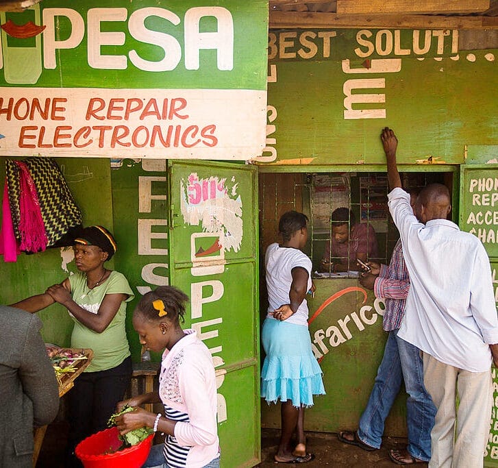 People stand outside a green M-Pesa stand.