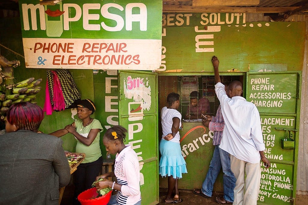 People stand outside a green M-Pesa stand.