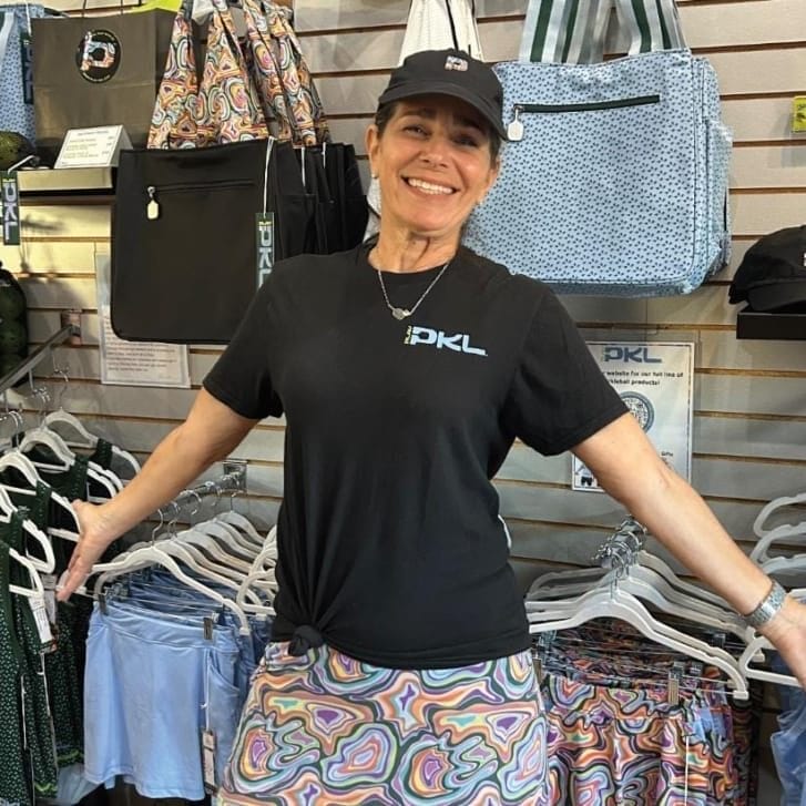 Portrait of Heidi Block wearing a black Play-PKL shirt and standing in front of her business's apparel.