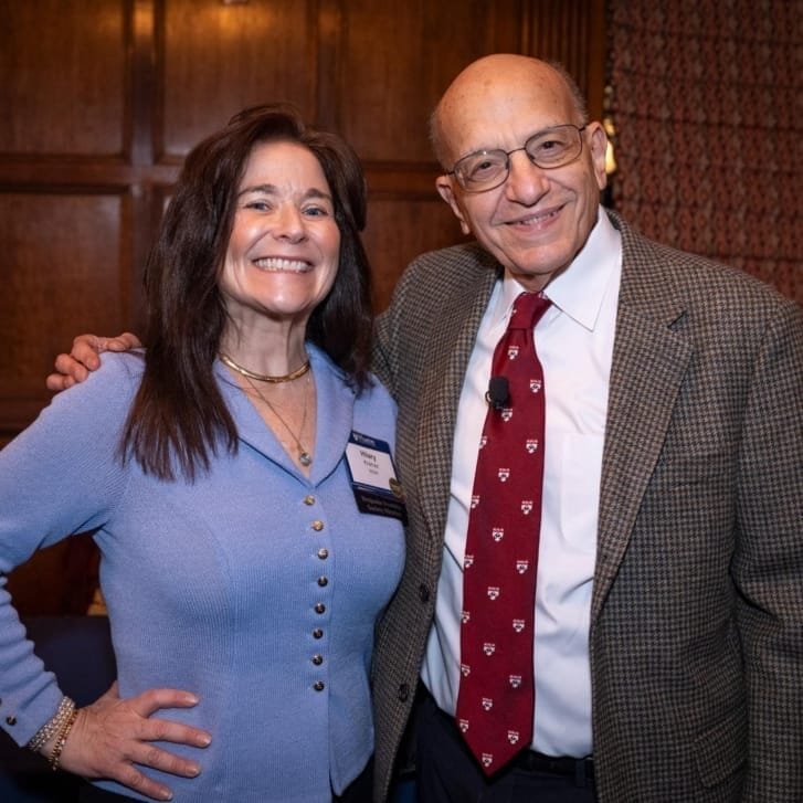 Hilary Kramer in a light blue sweater poses with Jeremy Siegel in a brown suit jacket, white shirt, and red tie with Penn shields on it.