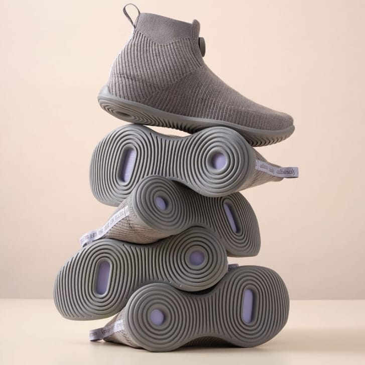 Five pairs of white high-top shoes stacked on top of each other in a column.