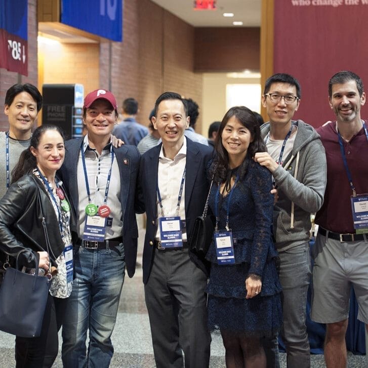 Nine attendees at Wharton Reunion Reimagined pose for a photo together in Huntsman Hall.