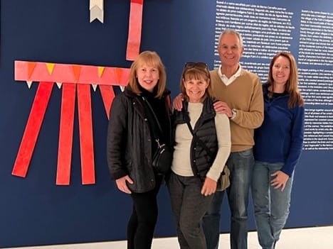 Four people in casual wear pose together for a photo.