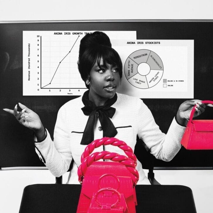 Wilglory Tanjong in a white jacket and with a black bow around her neck stands in front of a whiteboard holding a bright pink bag. Other bright pink bags are arranged on a table in front of her.