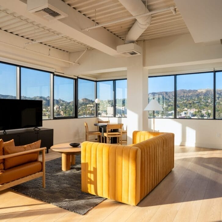 Living room with a yellow couch, TV, and table