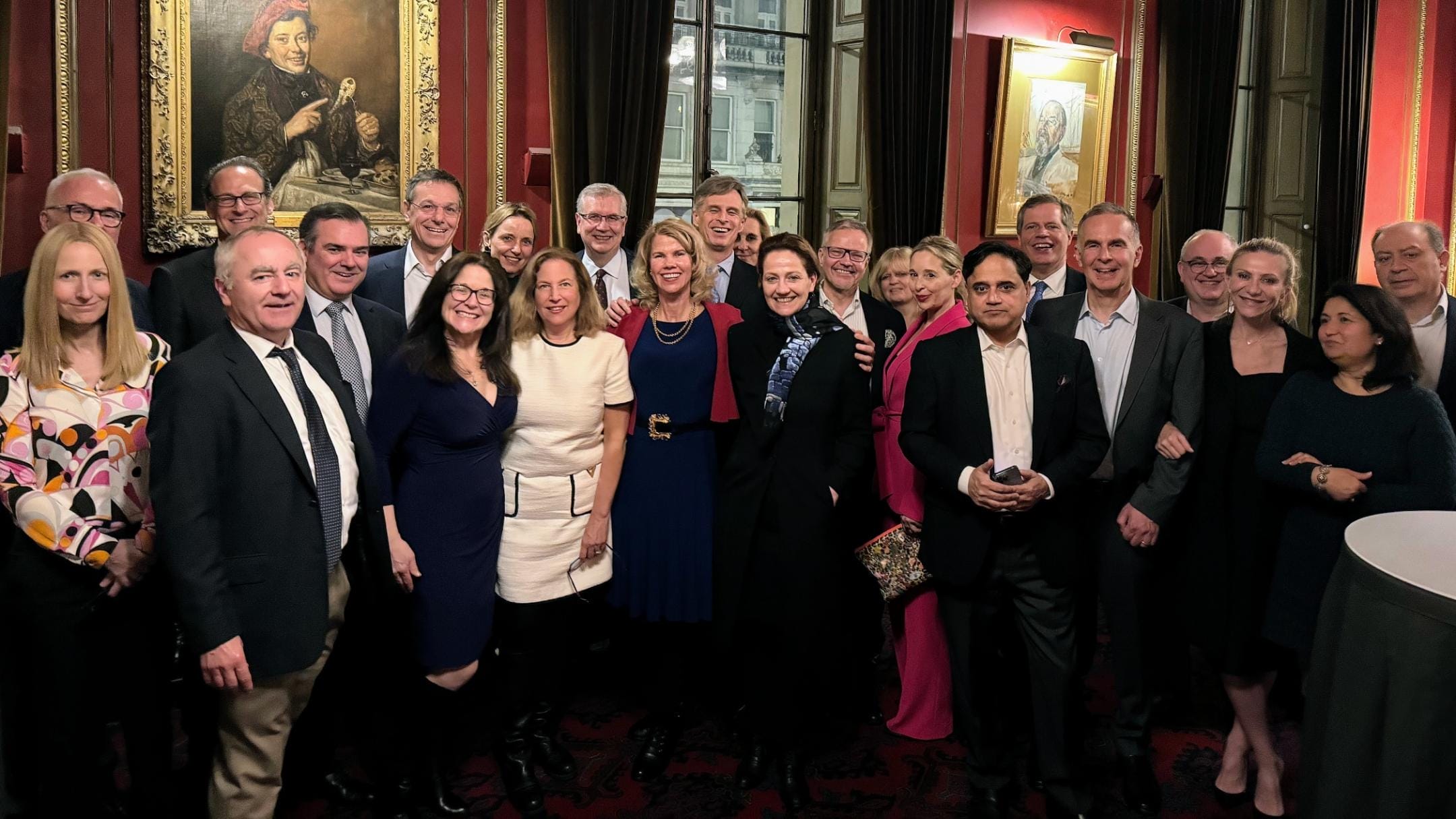 Two dozen people stand in a ballroom in business attire for a photo.