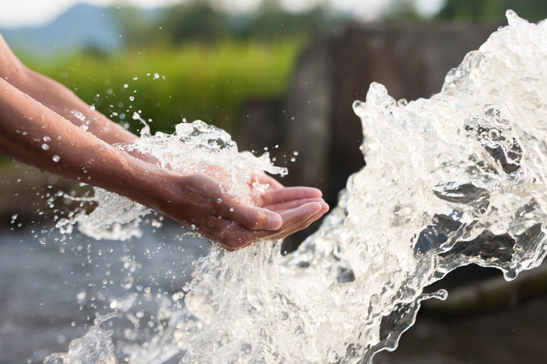 Hands cupped in front of a splash of water in a lake